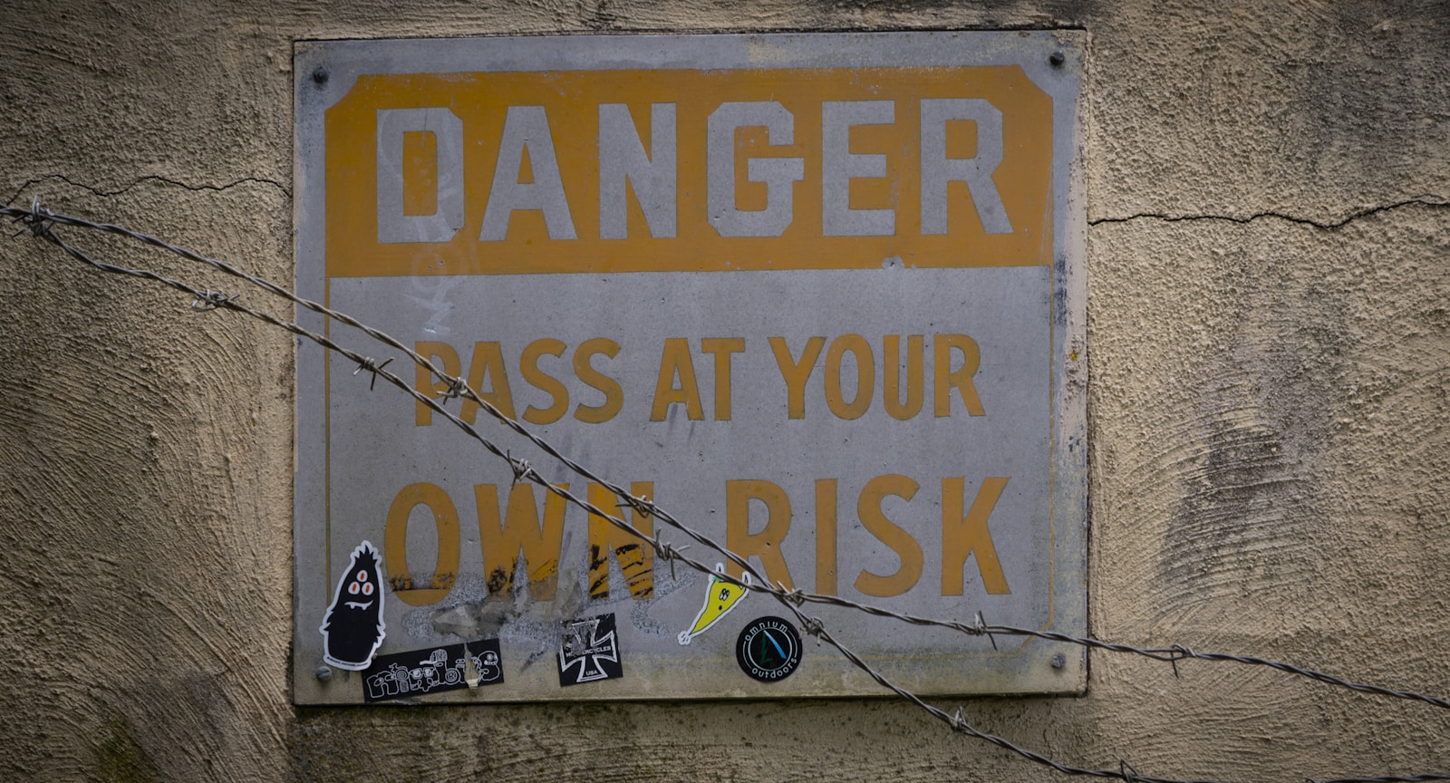 a sign on a wall that says danger pass at your own risk